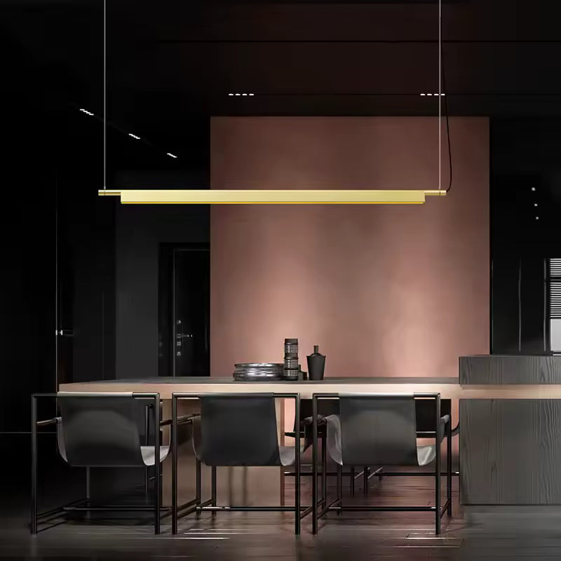 Suspension linéaire LED dorée au-dessus d’un îlot, dans un intérieur sombre au style moderne et sophistiqué