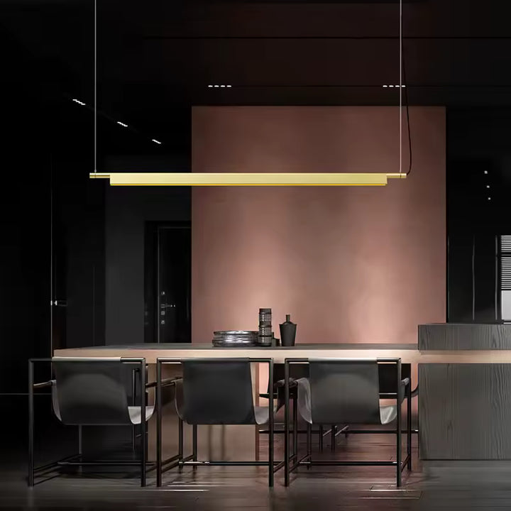 Suspension linéaire LED dorée au-dessus d’un îlot, dans un intérieur sombre au style moderne et sophistiqué
