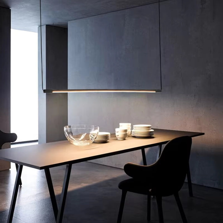 Ambiance tamisée autour d'une table avec une fine suspension linéaire LED noir mat.