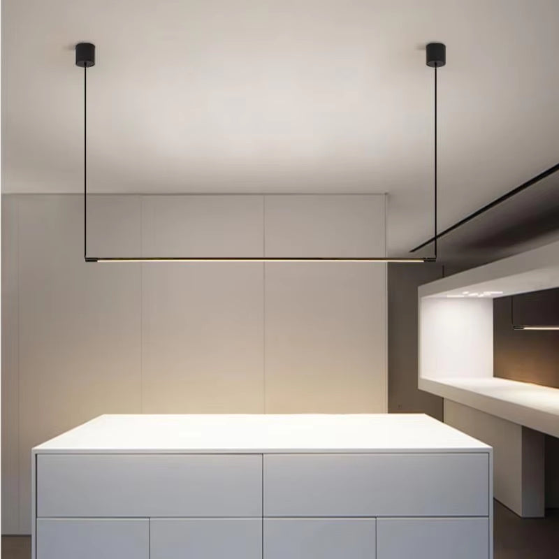 Suspension linéaire LED noir mat positionnée au-dessus d'un îlot de cuisine blanc.
