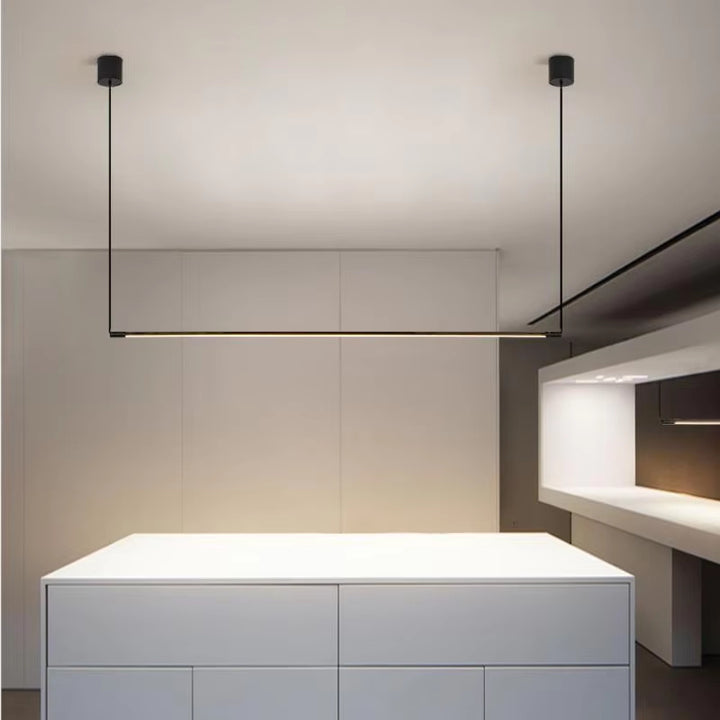 Suspension linéaire LED noir mat positionnée au-dessus d'un îlot de cuisine blanc.