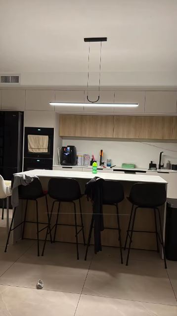 Suspension linéaire LED noire au design épuré, luminaire contemporain idéal pour éclairer un îlot de cuisine moderne.