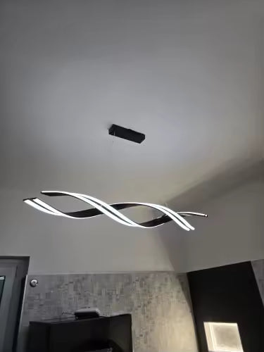 Vue en contre-plongée d'une suspension LED noire aux rubans lumineux croisés, au design futuriste et sculptural.