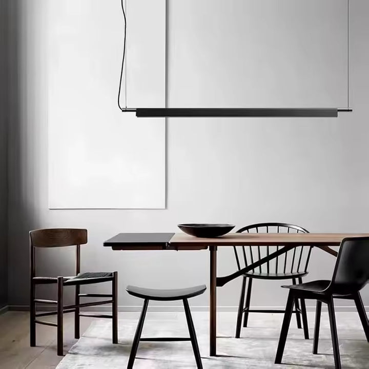 Suspension linéaire LED noire au-dessus d’une table, dans une salle à manger minimaliste et contemporaine