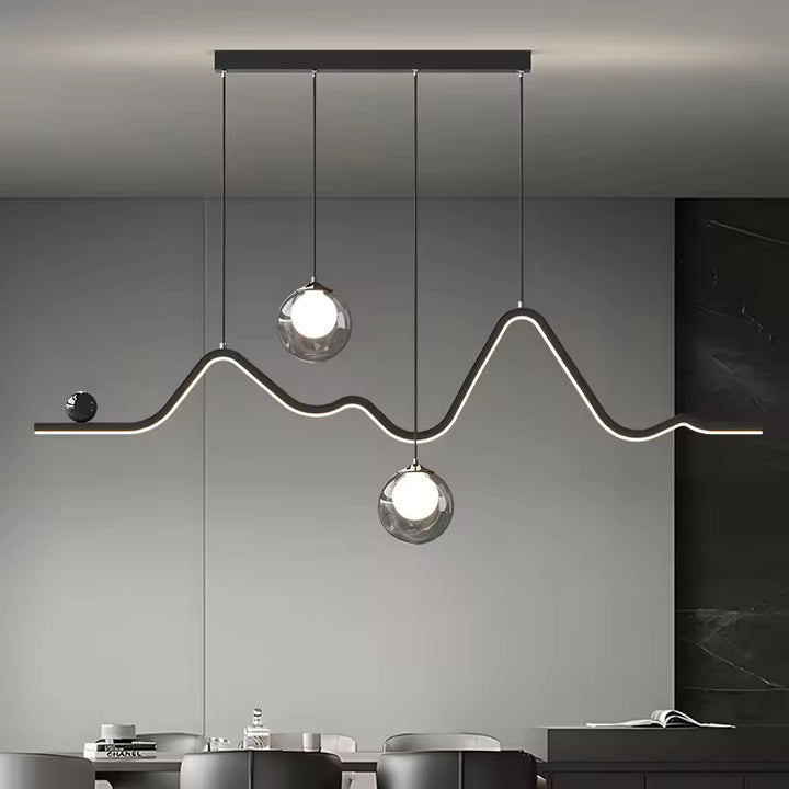 Au-dessus d'une table à manger, suspension graphique à ligne LED sinueuse et deux globes en verre au style contemporain.