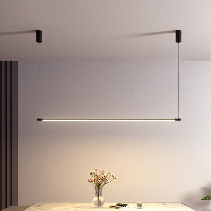 Suspension linéaire LED ultra fine créant en noir une ambiance chaleureuse au-dessus d'un meuble.