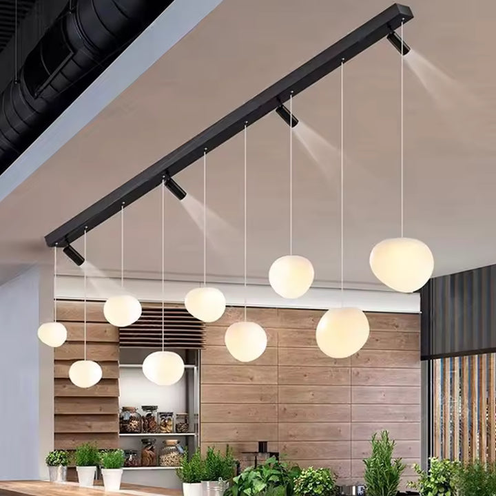 Composition contemporaine de globes opalins suspendus avec spots orientables sur longue barre noire