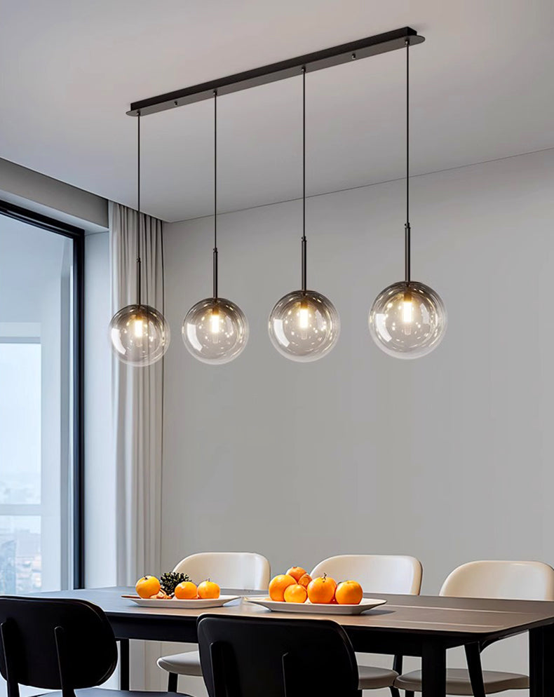 Suspension linéaire avec 4 globes en verre créant une ambiance cosy et lumineuse dans un espace repas.