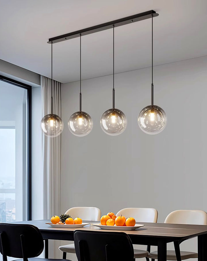 Suspension linéaire avec 4 globes en verre créant une ambiance cosy et lumineuse dans un espace repas.