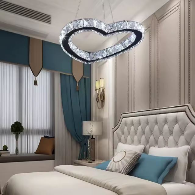 Suspension luminaire cœur en acier inoxydable et cristal, parfaite pour créer une ambiance élégante et romantique dans une chambre haut de gamme.