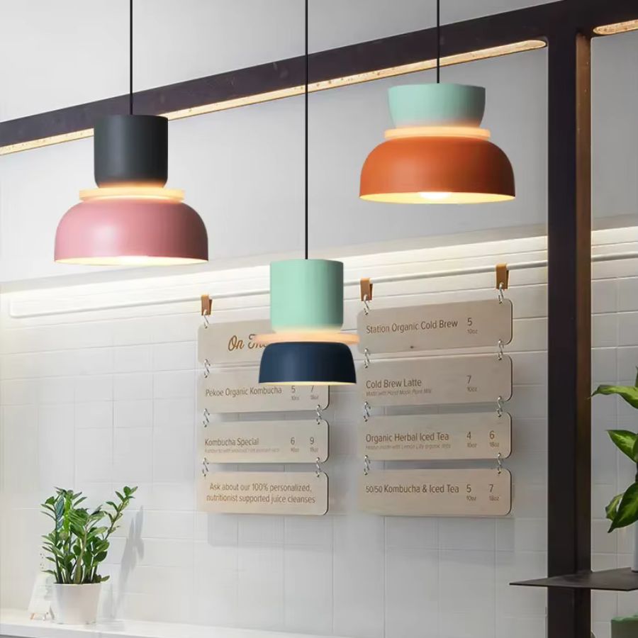 Dans un café au style rétro contemporain, trio de suspensions macaron colorées au design graphique