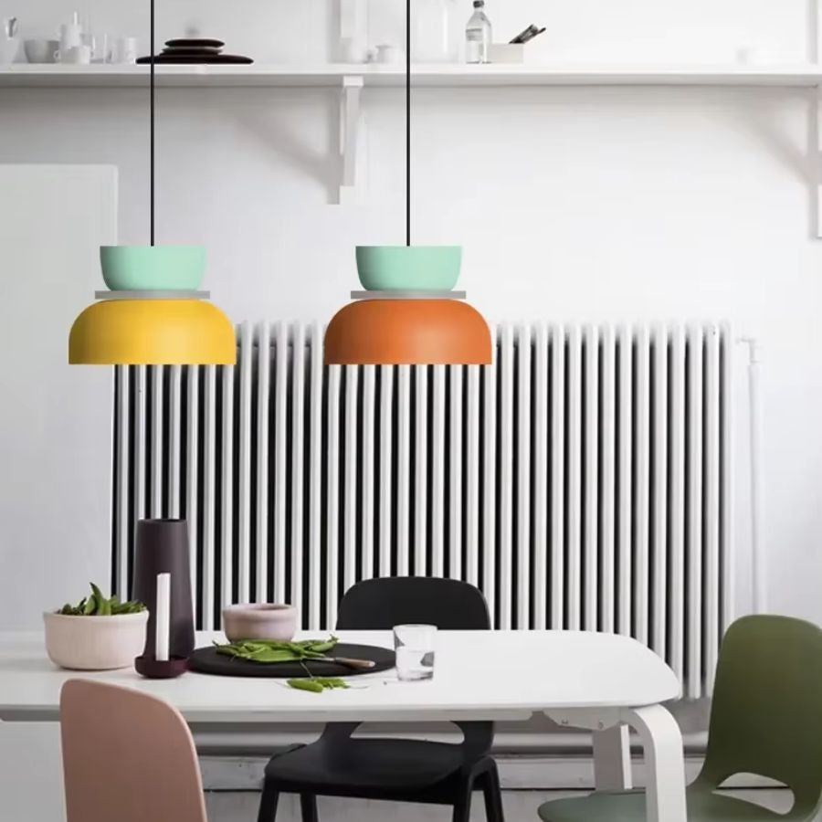 Deux suspensions macaron jaune et orange dans une salle à manger lumineuse au style scandinave contemporain
