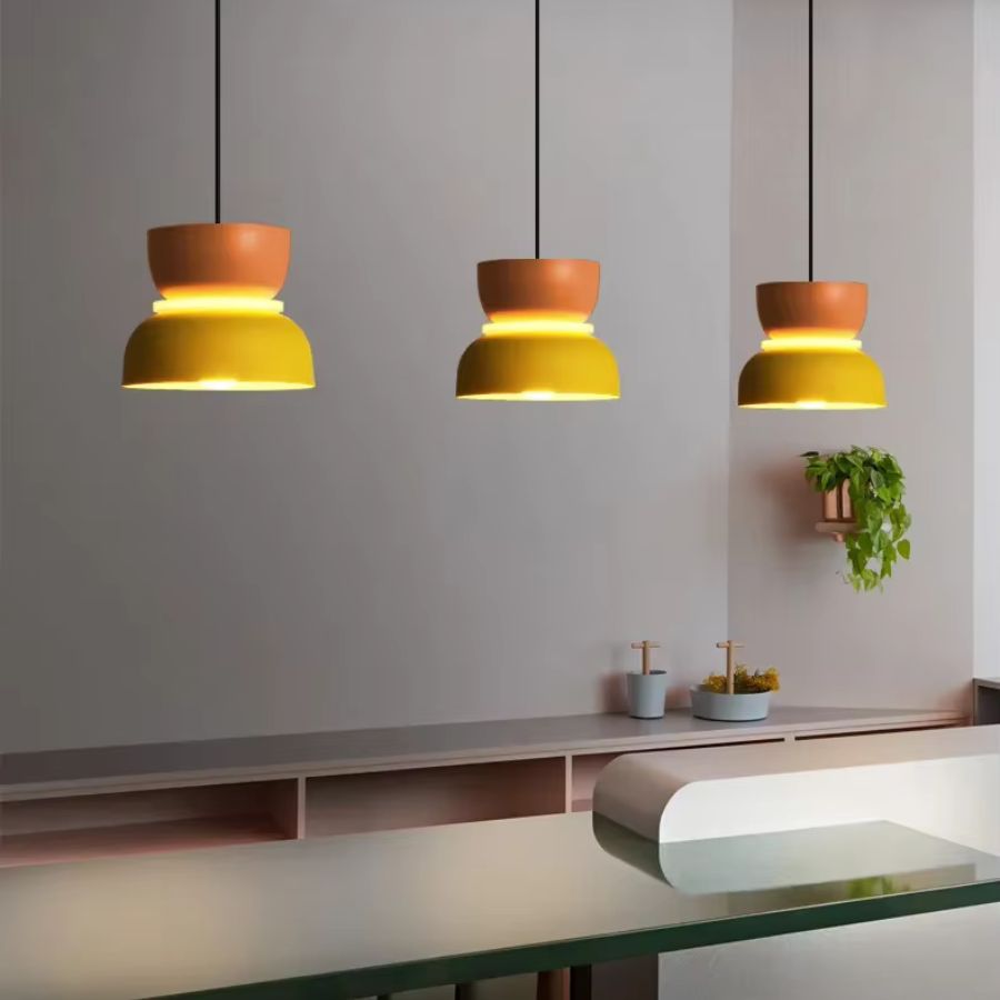 Trois suspensions macaron jaune et orange alignées dans une cuisine moderne au style minimaliste et rétro