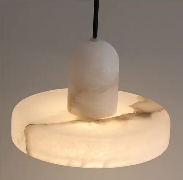 Gros plan sur une suspension en marbre blanc diffusant une lumière chaleureuse et élégante pour une ambiance raffinée.