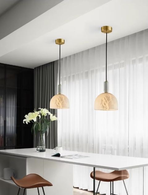 Duo de suspensions en marbre blanc illuminant un îlot de cuisine moderne avec une touche raffinée et naturelle.