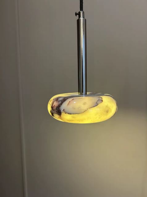Suspension en marbre diffusant une lumière chaude, au design contemporain inspiré des formes organiques et épurées