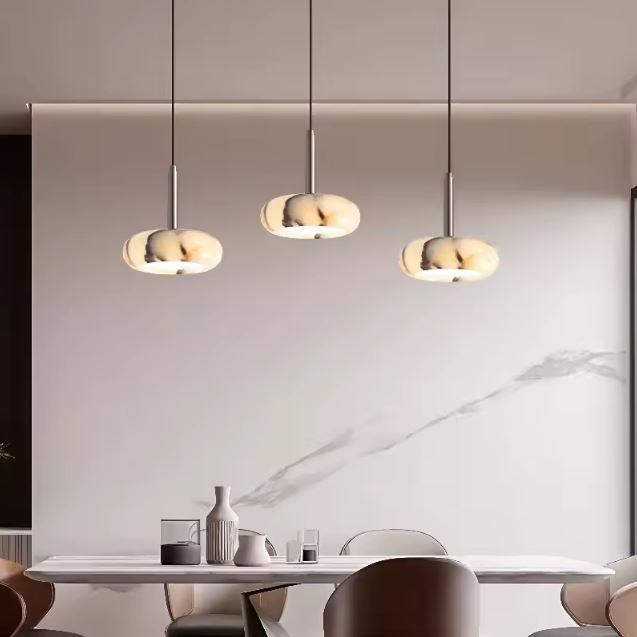 Trois suspensions en marbre au design contemporain au-dessus d'une table, idéales pour un îlot ou une salle à manger