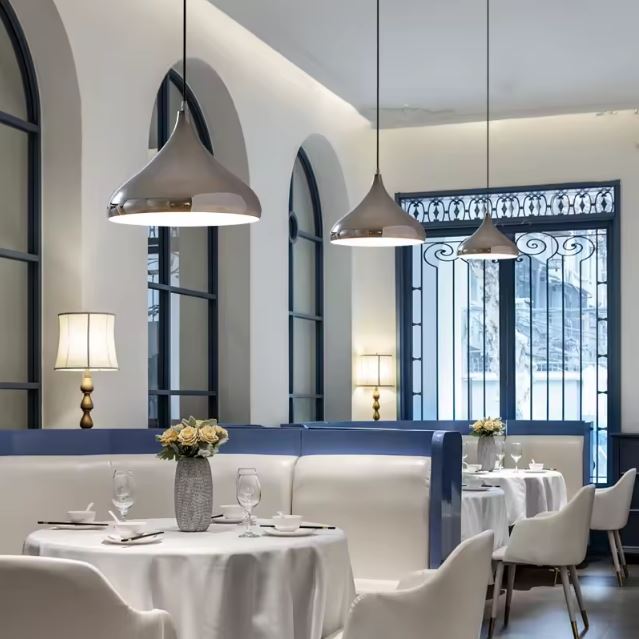 Suspensions en métal argenté illuminant un restaurant élégant avec une ambiance chic et raffinée, parfaite pour des dîners intimes.