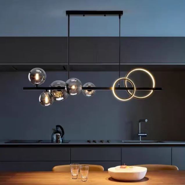 Suspension moderne avec anneaux LED et globes en verre fumé, offrant un éclairage chaleureux et élégant dans une cuisine design et épurée.