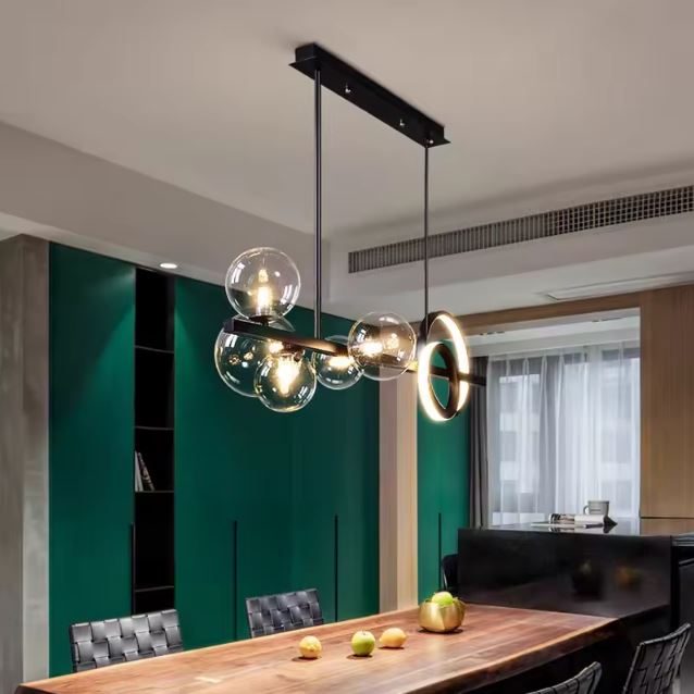 Suspension moderne avec anneaux LED et globes en verre transparent, offrant un éclairage design et chaleureux au-dessus d’une table en bois dans un intérieur contemporain et original.