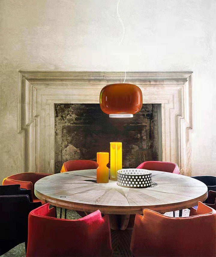 Suspension Monolithe Space Age orange laquée diffusant une lumière douce dans une salle à manger élégante.