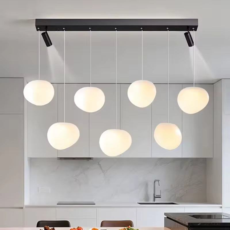 Avec ses globes opalins suspendus à différentes hauteurs, ce luminaire design moderne structure élégamment la cuisine