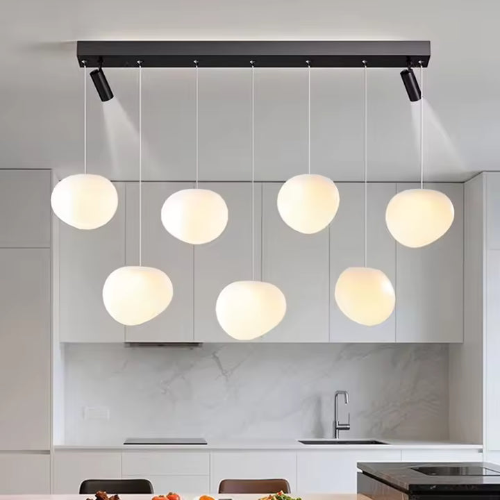 Avec ses globes opalins suspendus à différentes hauteurs, ce luminaire design moderne structure élégamment la cuisine