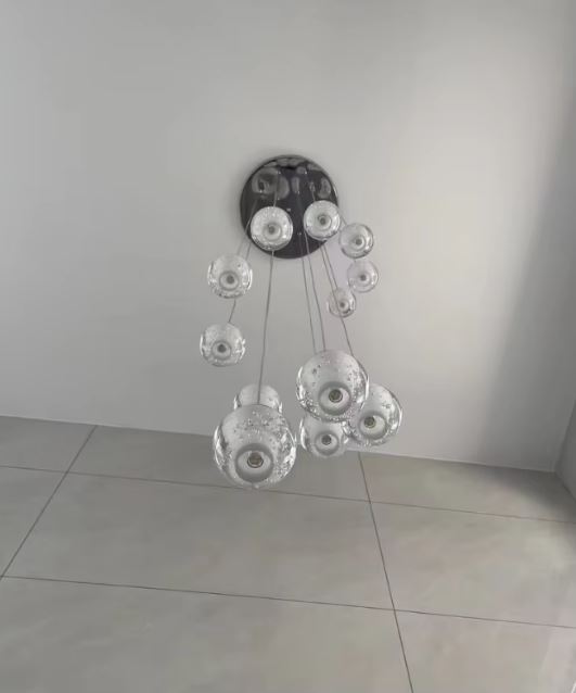 Suspension multiple à globes en verre bullé sur platine noire, luminaire design moderne au rendu aérien.