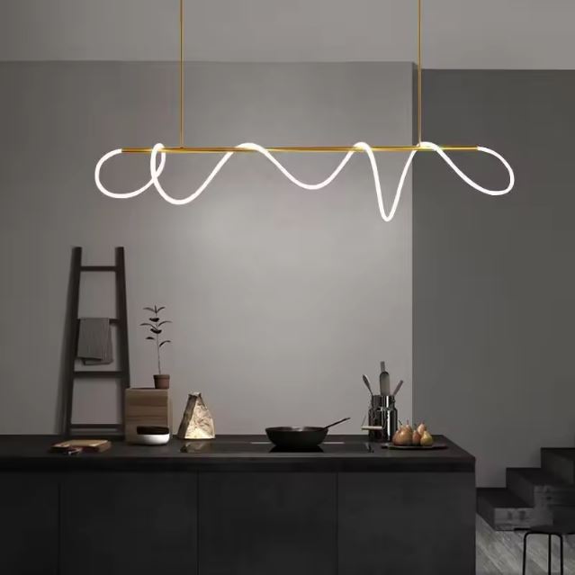 Suspension néon LED dorée au design ondulé, idéale pour une cuisine moderne avec mobilier noir.