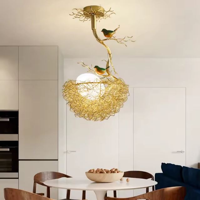 Suspension nid d'oiseau design en métal doré avec oiseaux, parfaite pour éclairer un salon moderne.