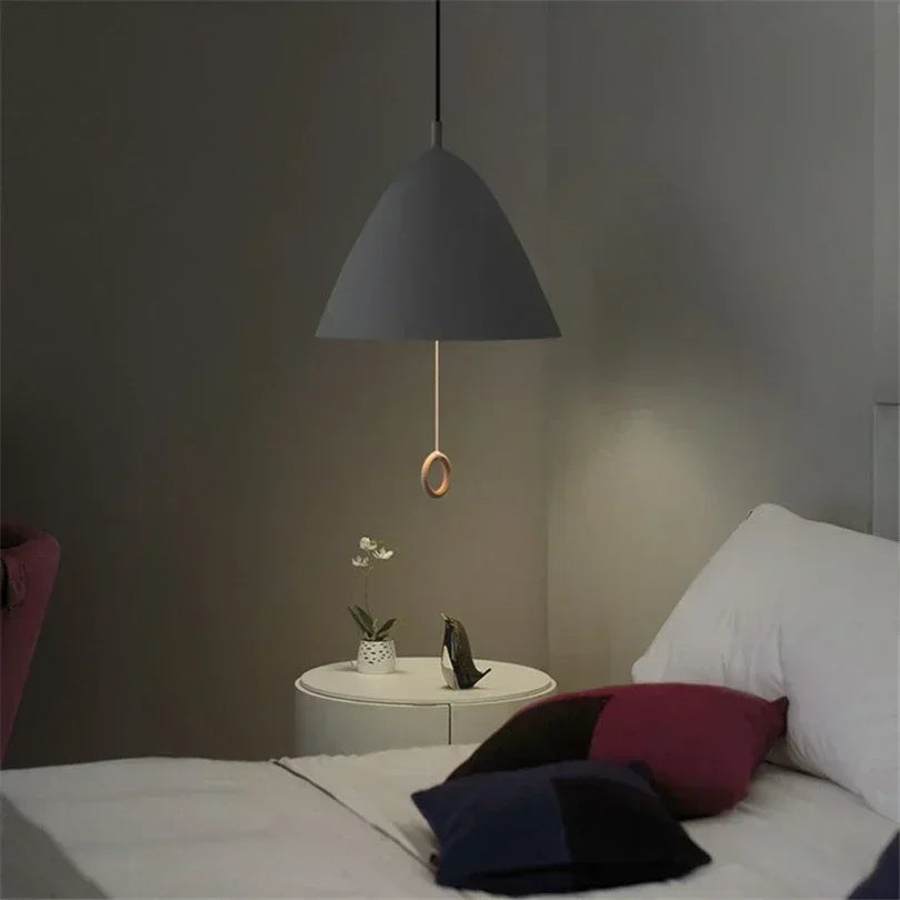 Suspension noire avec tirette en bois placée dans une chambre cosy aux tons feutrés.