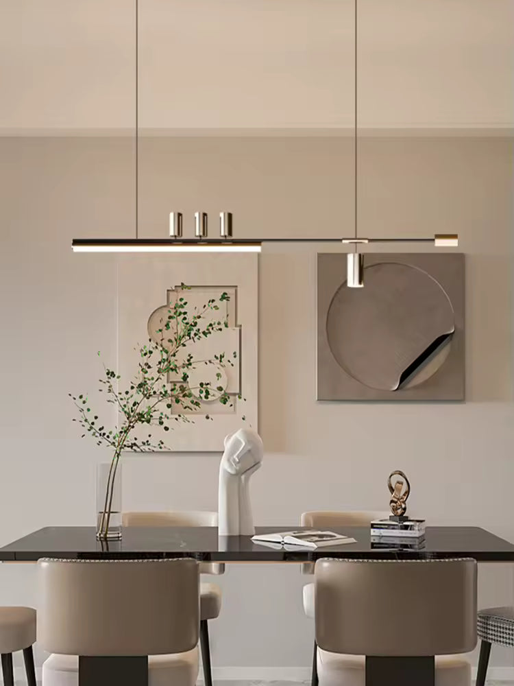 Luminaire noir et doré au dessin asymétrique et raffiné, suspendu au-dessus d’une table dans une salle à manger design
