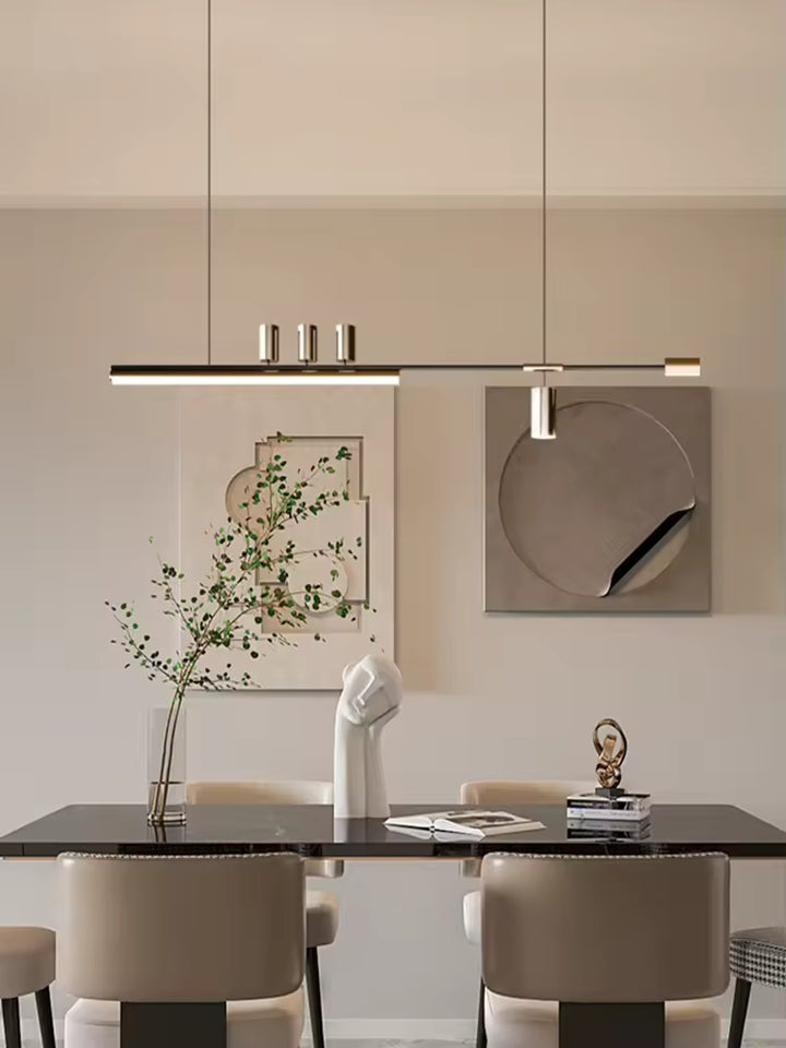 Luminaire noir et doré au dessin asymétrique et raffiné, suspendu au-dessus d’une table dans une salle à manger design