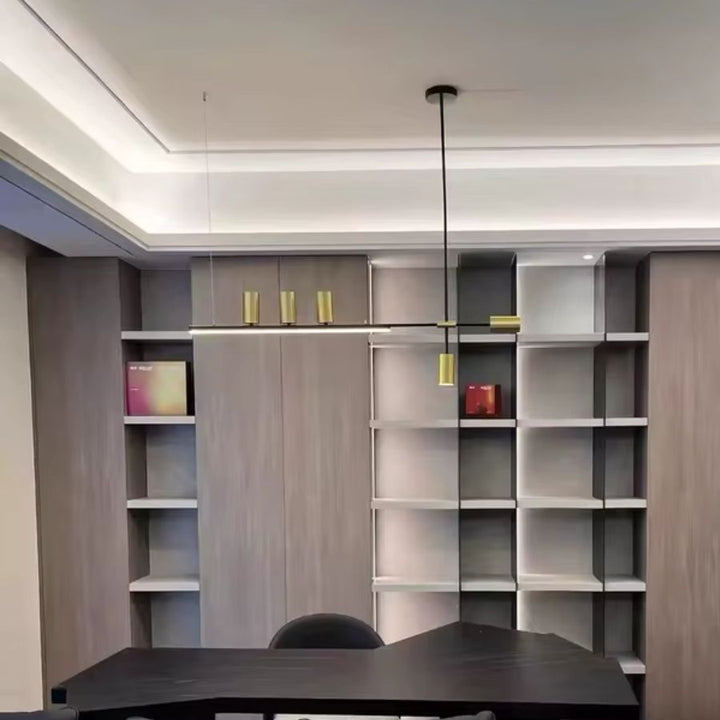 Luminaire suspendu noir et doré au style graphique et moderne installé au-dessus d’une table de salle à manger