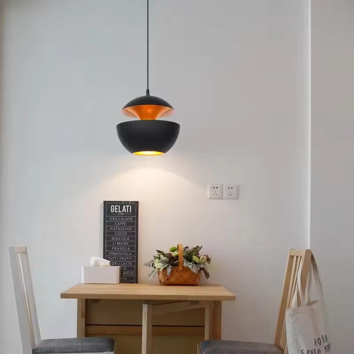 Au-dessus d’une table, suspension noire à double coque métallique et intérieur cuivré au style contemporain