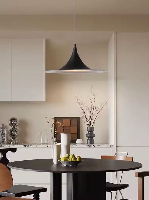 Suspension noire à large plateau au-dessus d’une table ronde, avec une influence bauhaus et un style contemporain épuré.