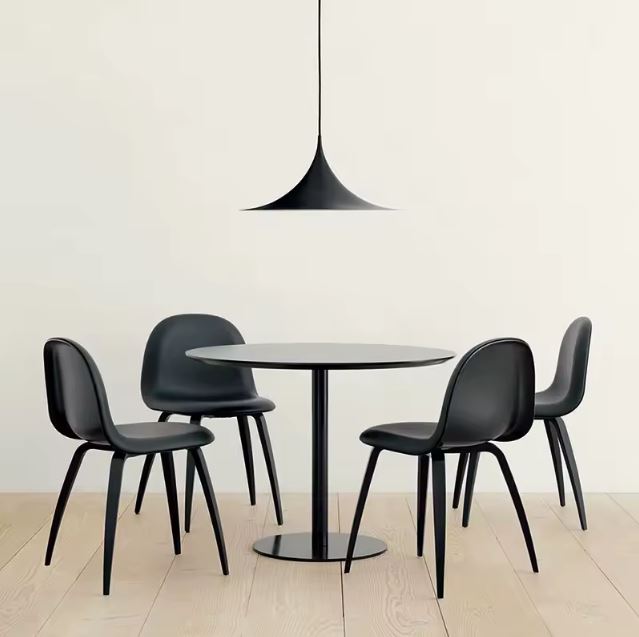 Suspension noire effilée au-dessus d’une table ronde, dans un esprit bauhaus, minimaliste et contemporain.