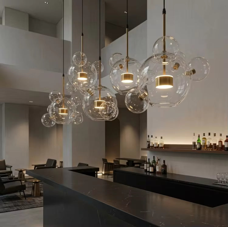 Au-dessus d'un comptoir noir, cinq suspensions à bulles en verre soufflé et finitions dorées créent un décor chic et moderne.