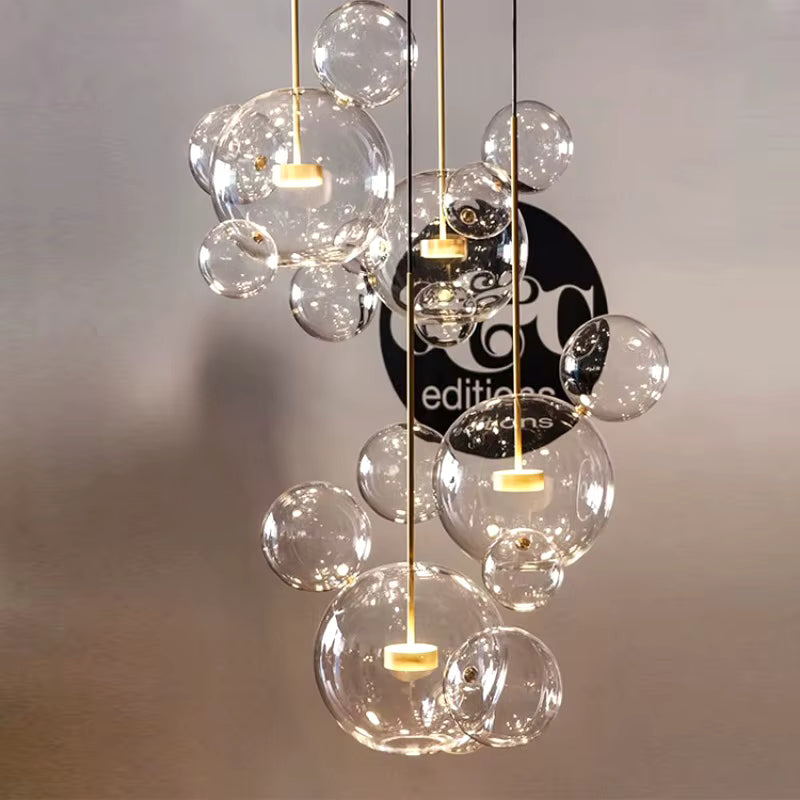 Composition en cascade de suspensions à bulles de verre soufflé transparent, aux détails dorés et au design sculptural.