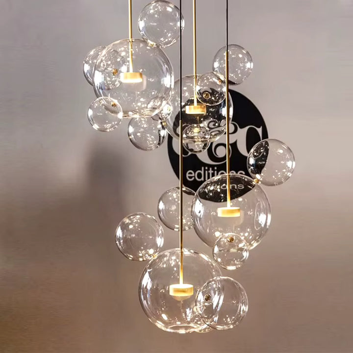 Composition en cascade de suspensions à bulles de verre soufflé transparent, aux détails dorés et au design sculptural.