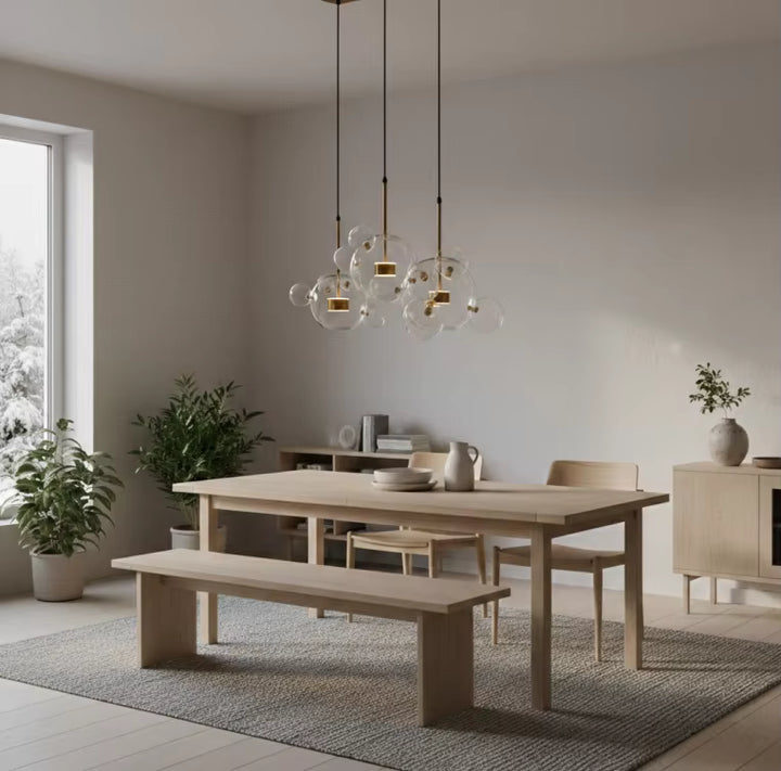 Au-dessus d'une table en bois clair, trois suspensions à bulles de verre soufflé subliment une salle à manger scandinave.