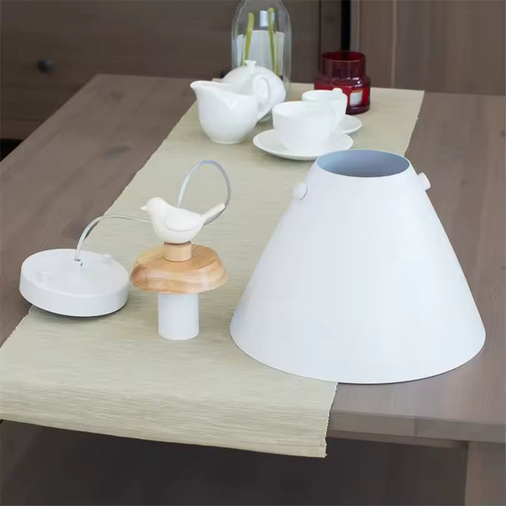 Vue des éléments du luminaire suspendu avec abat-jour conique blanc, détails en bois naturel et petit oiseau décoratif