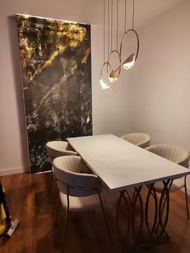 Suspension dorée à trois oiseaux lumineux suspendue au-dessus d'une table à manger design, dans un intérieur contemporain chaleureux.