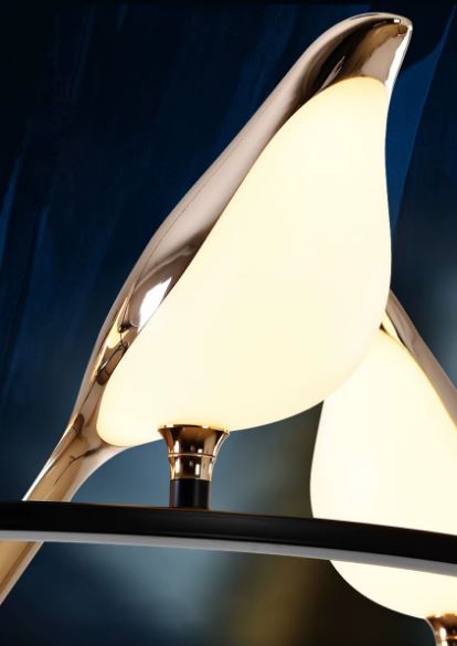 Zoom sur un oiseau lumineux en verre blanc et doré, détail élégant d’une suspension design sculpturale et raffinée.