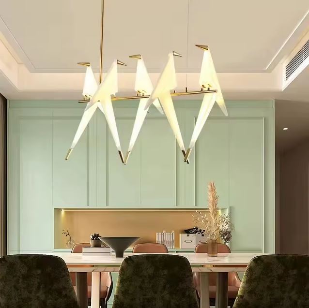 Suspension oiseau origami design avec des oiseaux lumineux sur une branche dorée, parfaite pour éclairer une salle à manger moderne.