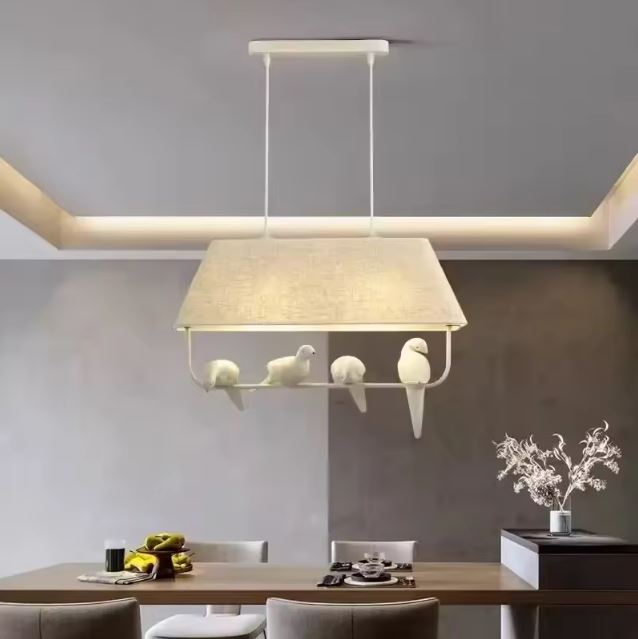 Suspension luminaire moderne avec des oiseaux sur branche, parfaite pour illuminer une table à manger contemporaine.