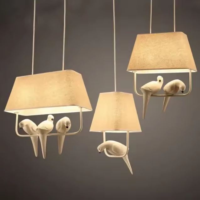 Trio de suspensions lumineuses avec oiseaux sur branche, parfaites pour une décoration élégante et classe.