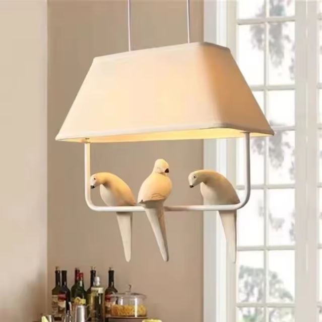 Suspension luminaire avec trois oiseaux sur branche, idéale pour une décoration lumineuse et élégante dans une salle à manger.