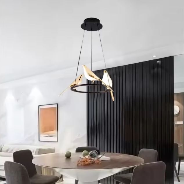 Suspension ronde à trois oiseaux dorés perchés, au style poétique et contemporain, parfaite au-dessus d’une table de salle à manger.
