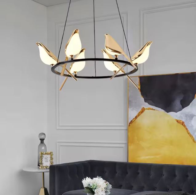 Suspension circulaire avec oiseaux dorés lumineux, idéale pour salon moderne avec canapé capitonné et déco artistique.